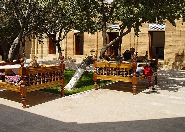 Cortile tradizionale con comodi tapchan sotto gli alberi ombrosi